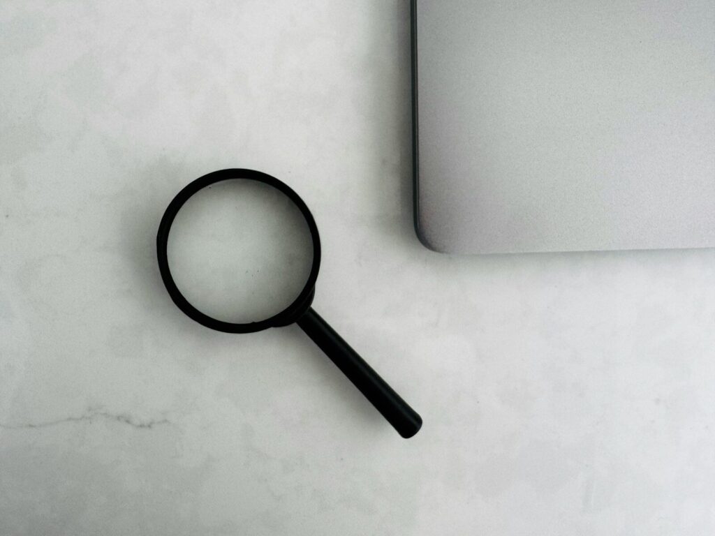 Magnifying glass sits near a laptop on a table